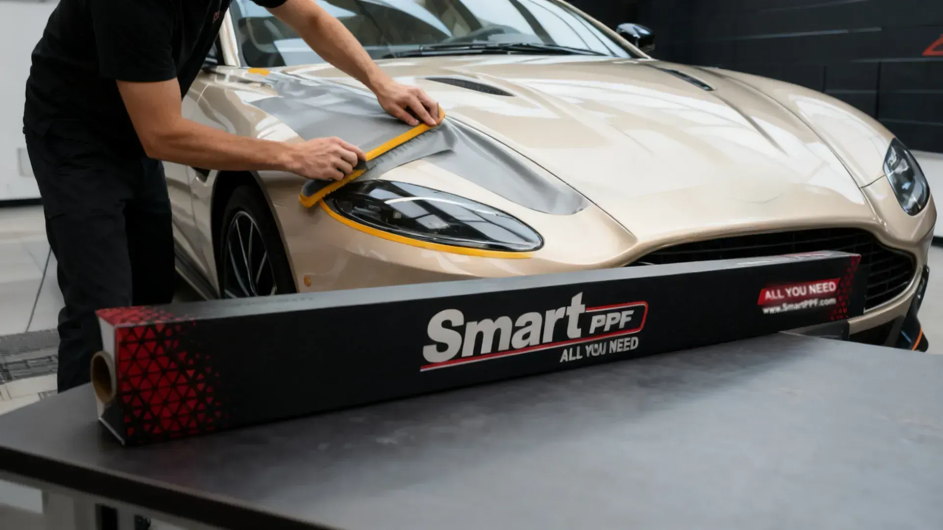 Warm grey satin film applied across a grand coupe hood, Smart PPF box on the work table