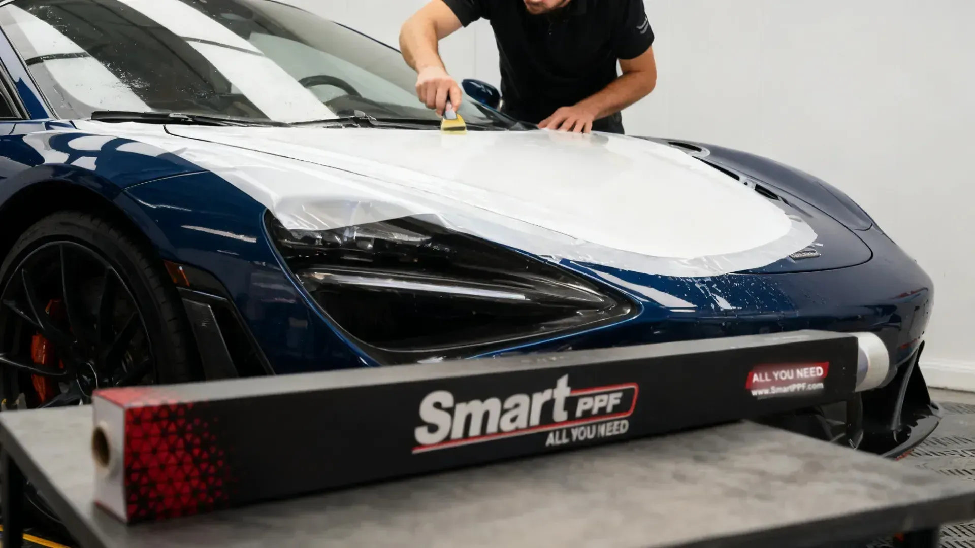 Pearl white colour film applied over a dark supercar hood, Smart PPF box in the foreground